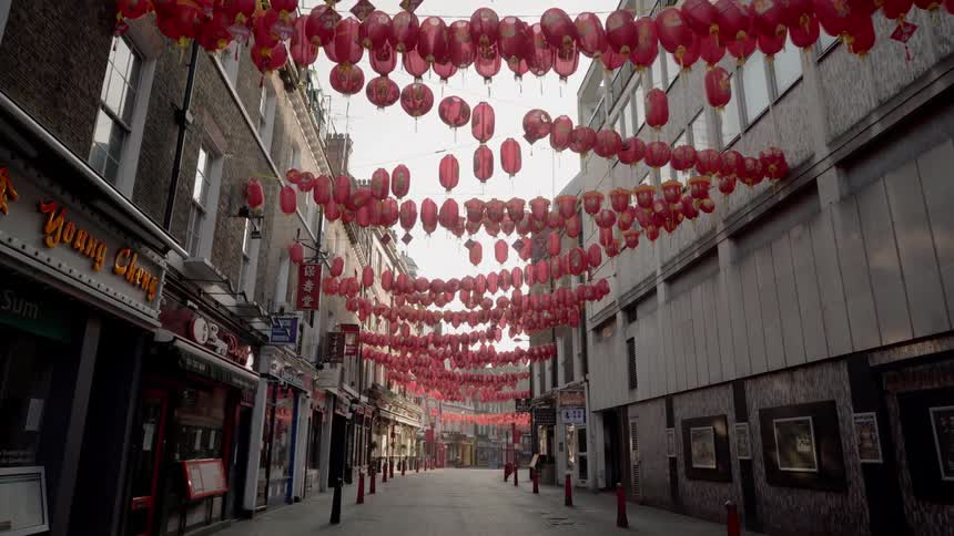 Red lanterns hang above the street strung between buildings in an empty chinatown