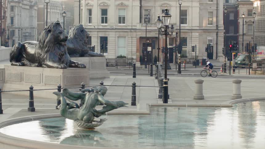 A bicyclist drives past a fountain in an empty city town square