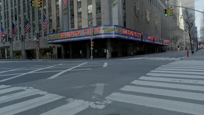 A single pedestrian is the only person walking through an empty intersection in new york city