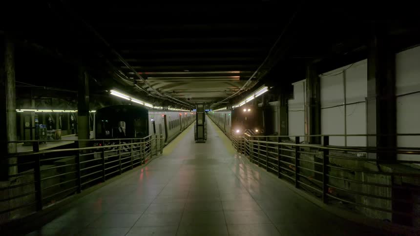 A subway train slowly pulls into an empty station