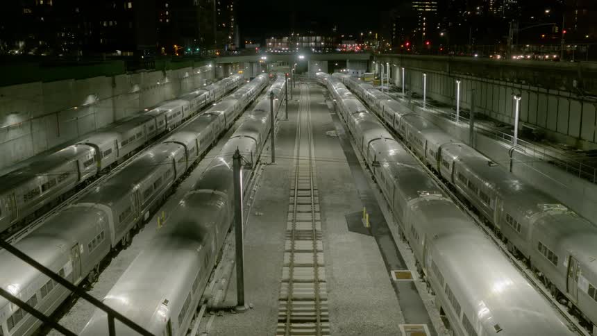 A train yard with trains at night with buildings in the background
