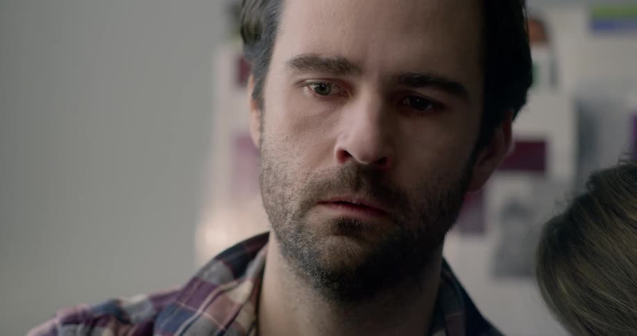 A distraught man sitting while another person leans on his shoulder