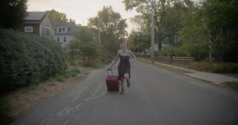 A woman races down the street pulling her luggage