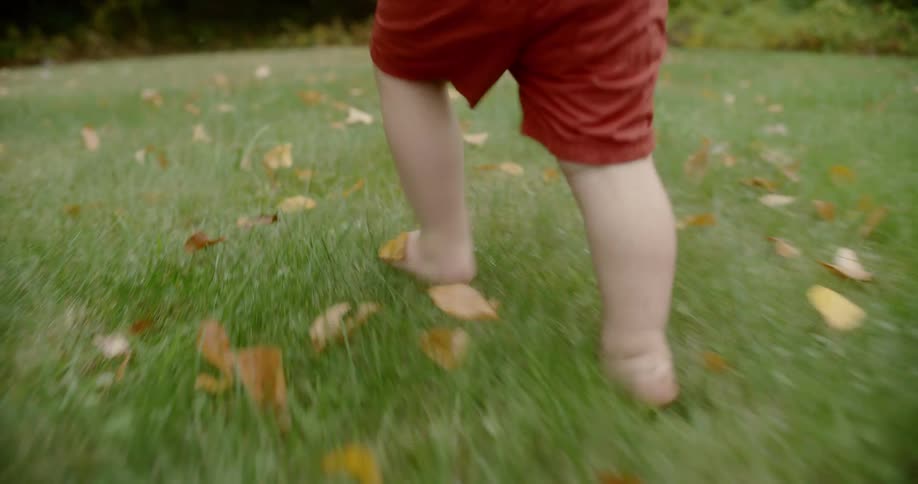 A young child runs barefoot through the lawn