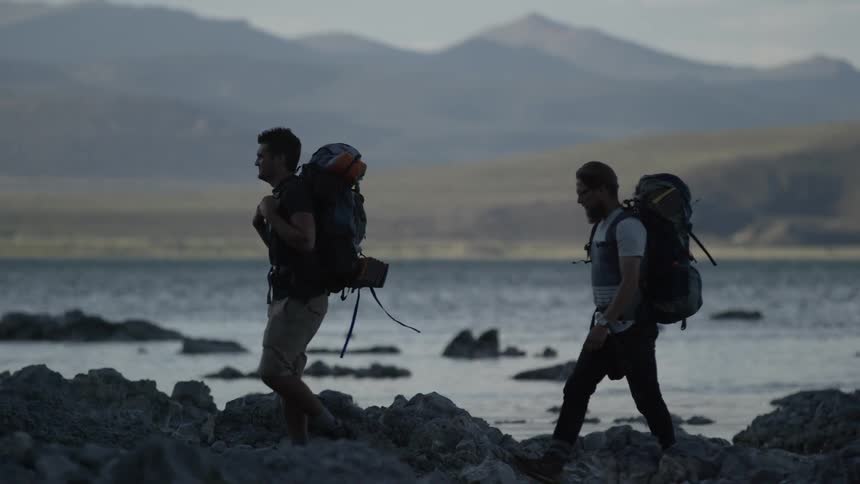 Two guys backpacking along the water