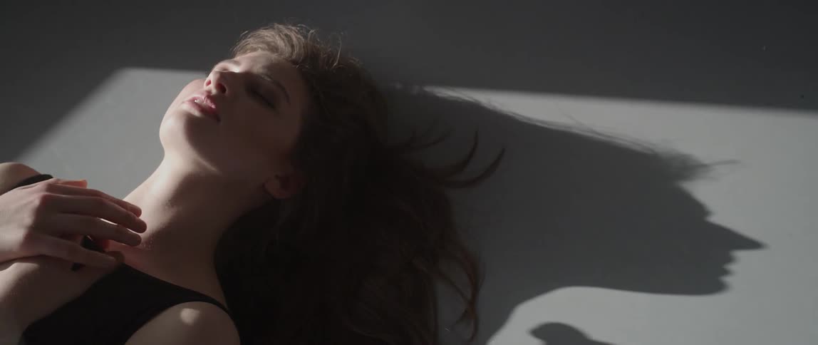 A woman lays on the floor with sunlight on her face