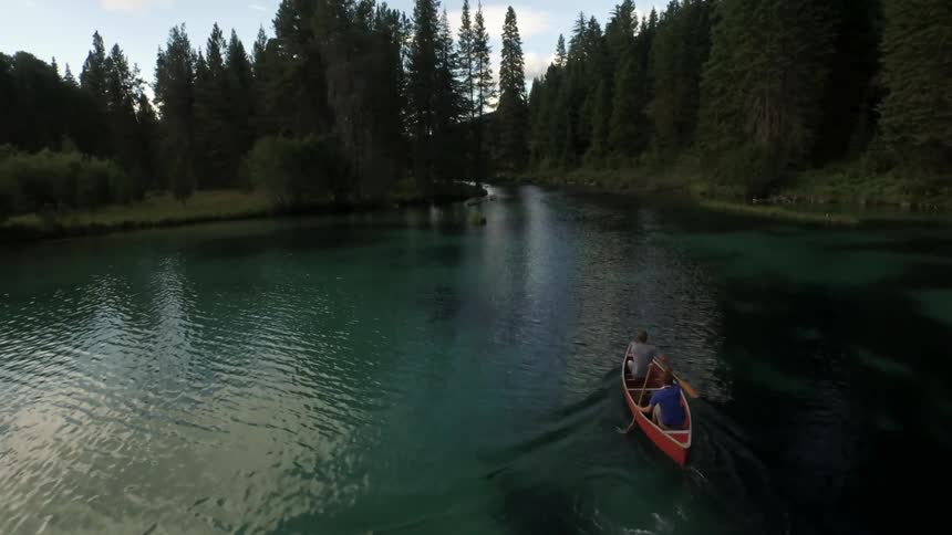 Two people are rowing a boat across a lake on a cloudy day