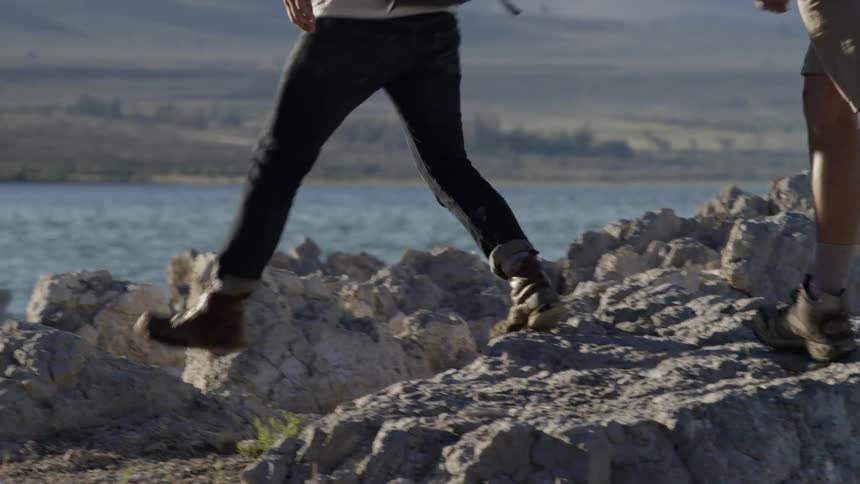 Two men with backpacks walk up rocks