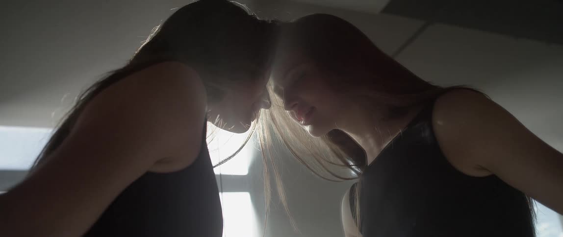 A woman slowly puts her head against a mirror then raises her arms to her chest