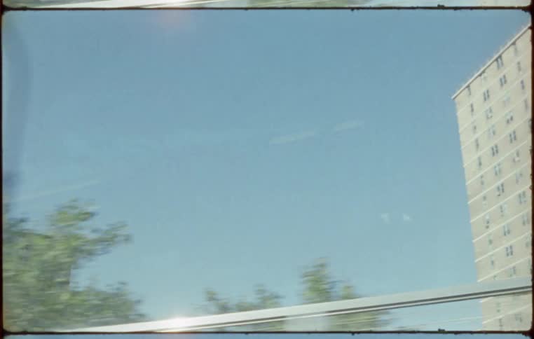 Views of a city are captured from inside a passing train