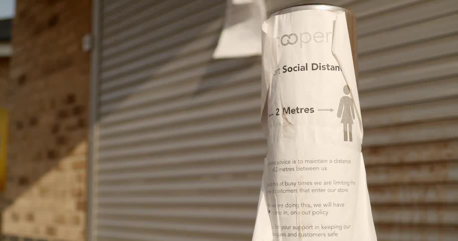 A social distancing sign hangs on a pole