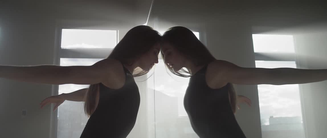 A woman dances in front of a window