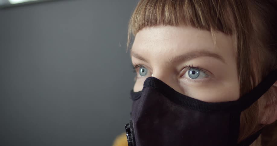 A short haired woman in a black face mask
