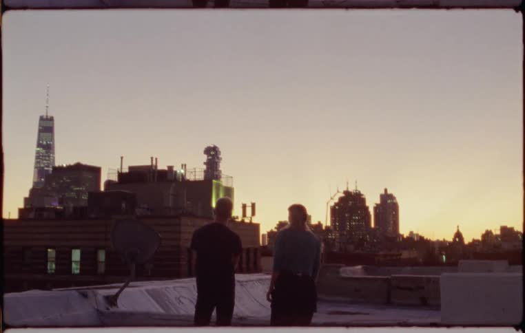 Two people stand on a rooftop