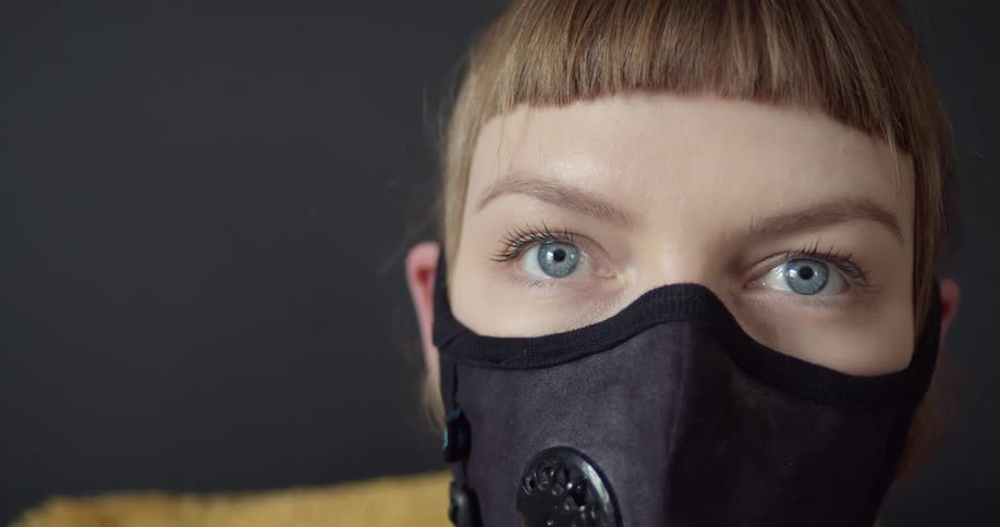 Woman sits in yellow chair wearing face mask