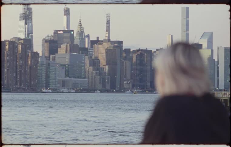 Blonde woman standing on the promenade watches city skyline