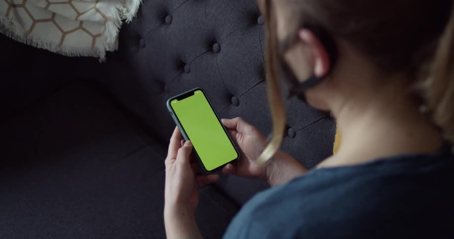 Woman wearing a black face mask uses a smartphone in the living room at home