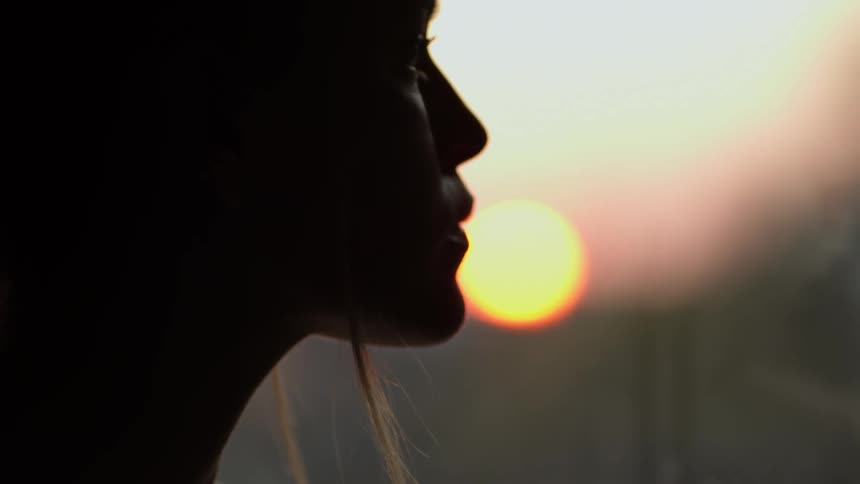 Womans silhouette turns her head at sunset