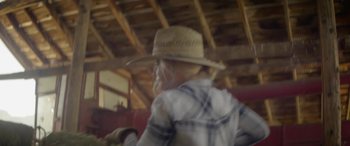 A woman picking up and moving a bale of hay