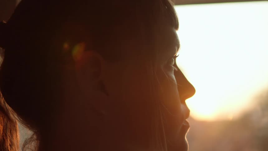 A woman stands and looks out the window