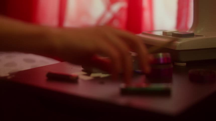A person retrieving a cigarette and lighter from a bedside table