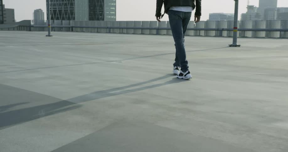 A young man walks down a quiet block in a city