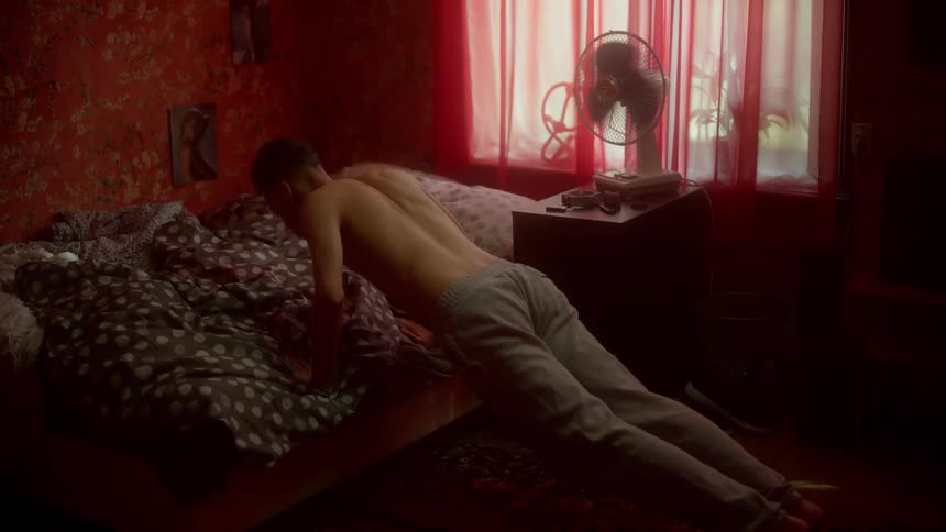 A man in his bedroom doing push ups on his bed