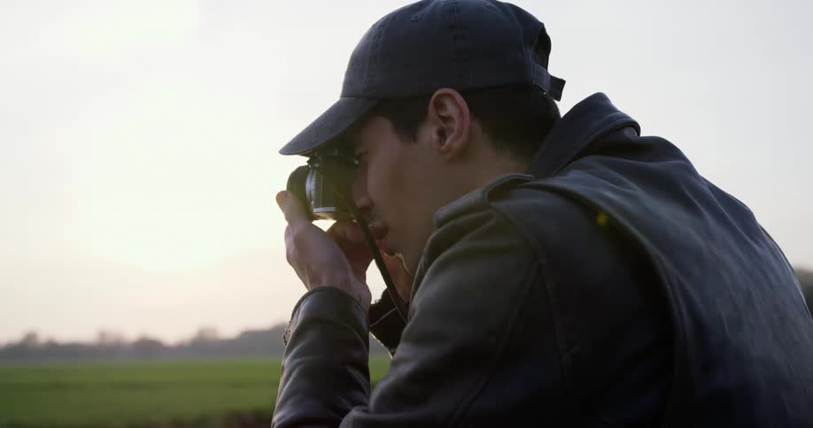 Photographer stands near river focusing his camera