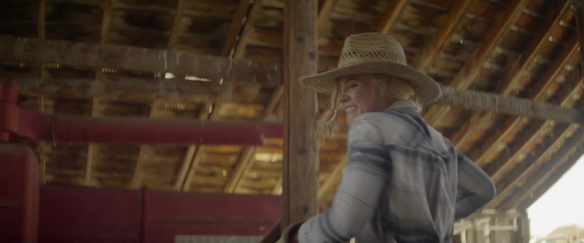 Young woman carries hay bale in barn