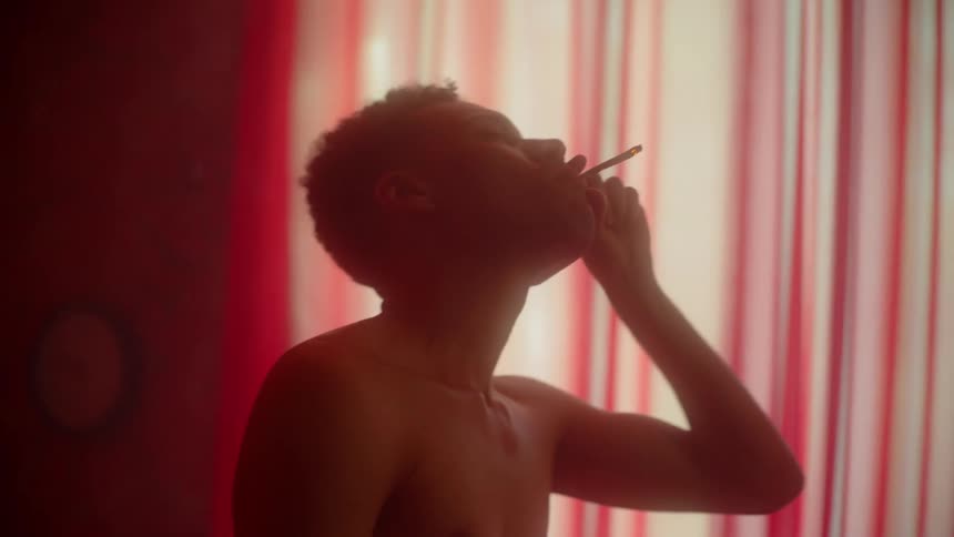 Black man smoking cigarette while lonely dancing on a pink room