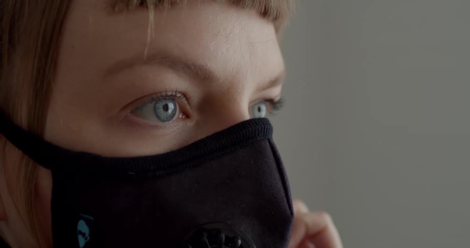 A woman putting on a face mask