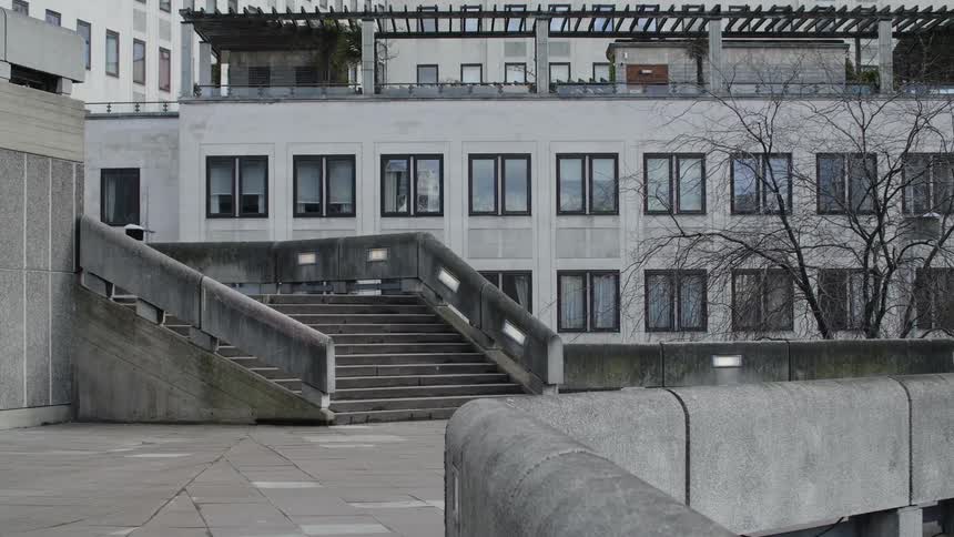 People walk across plaza between outdoor steps and concrete fence