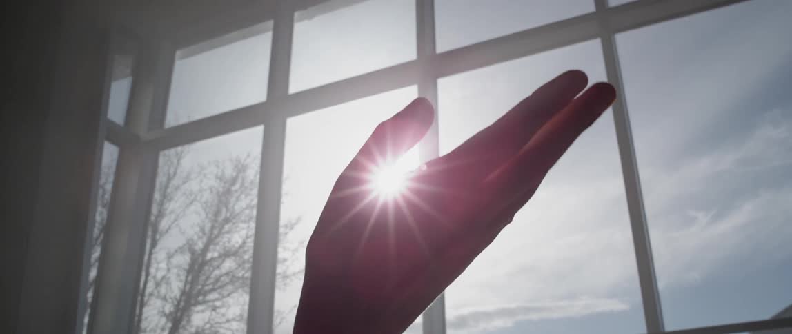 A hand twisting before a window
