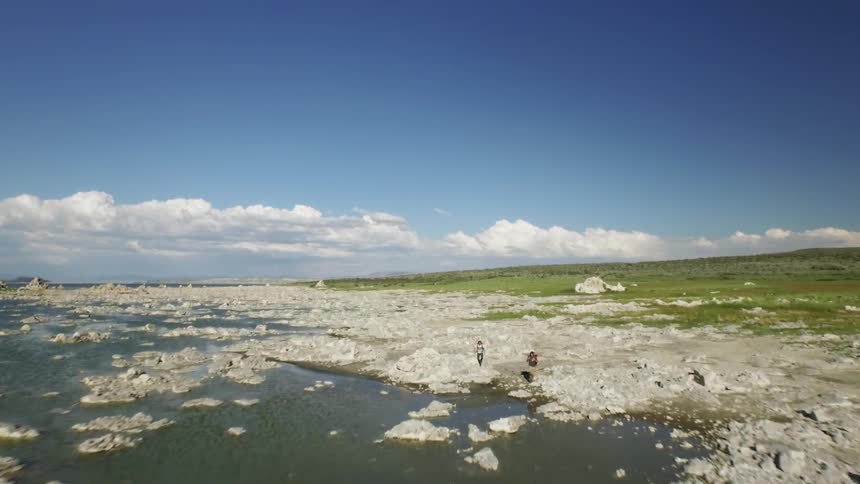 A rocky shore next to green grass on a party cloudy day