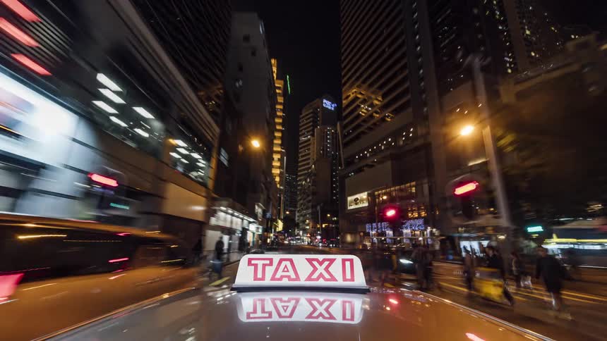 A taxi drives around a large city at night