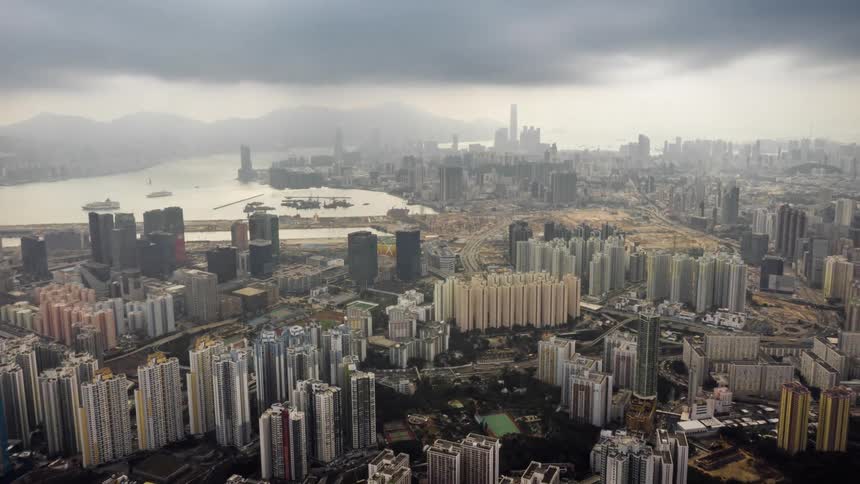 River winds between mountains and city during foggy day
