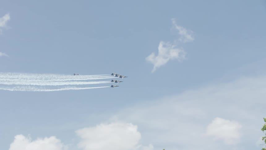 Jets fly in formation above buildings on slightly cloudy day