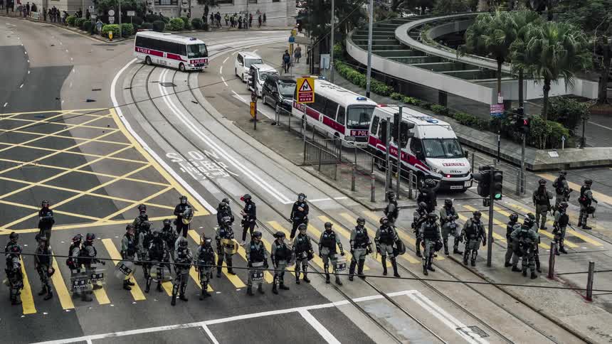 Large group of police in riot gear block crosswalk on street