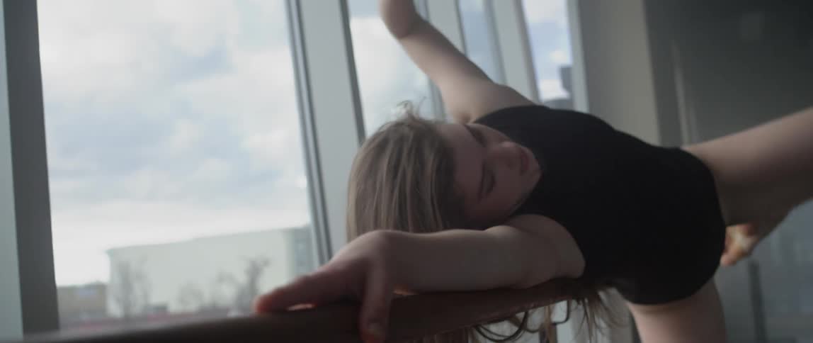 A woman in black dances in front of a window