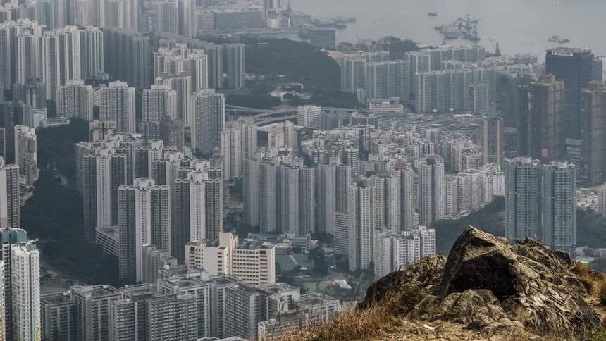 A hill overlooking a coastal city with buildings and a harbor in the background