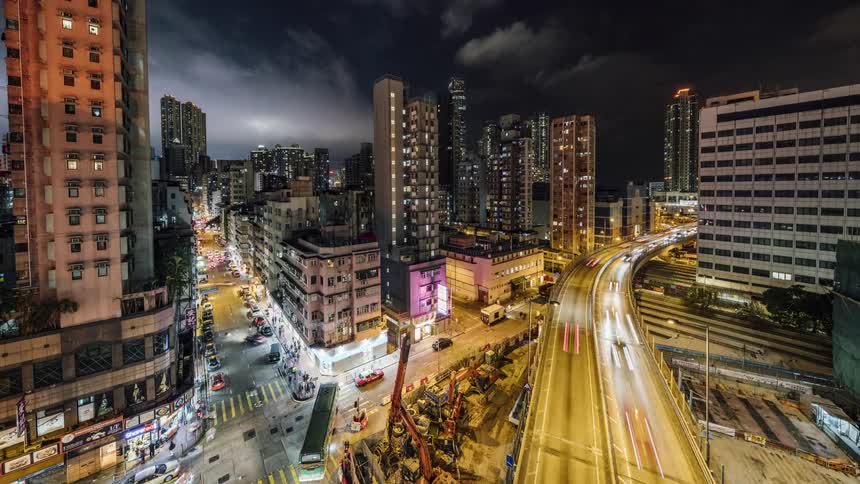 Aerial view of the people walking down the busy street and the vehicles driving on the highway at night in the city