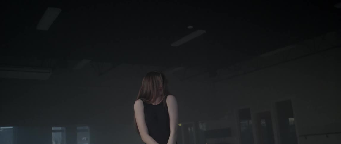 A woman is stretching in a dark area