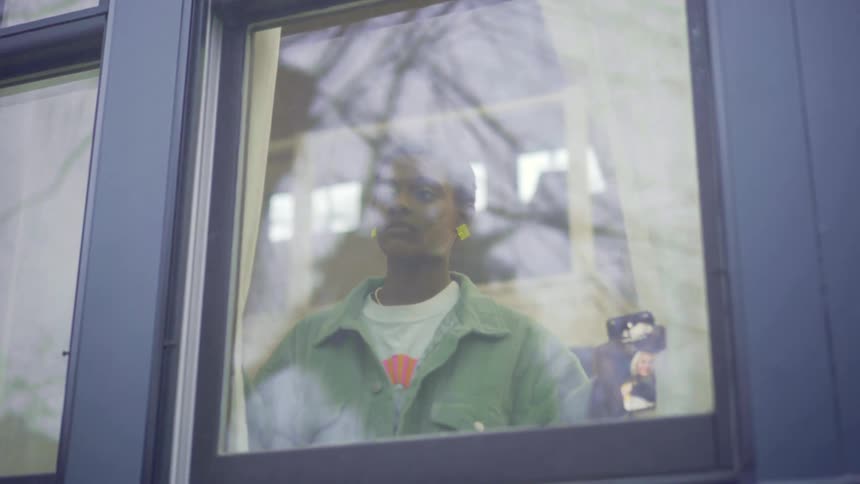 Woman inside house open curtains to see outside through window