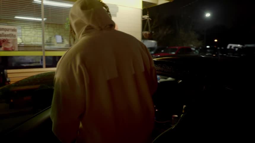 Two men in front of a store getting into a car