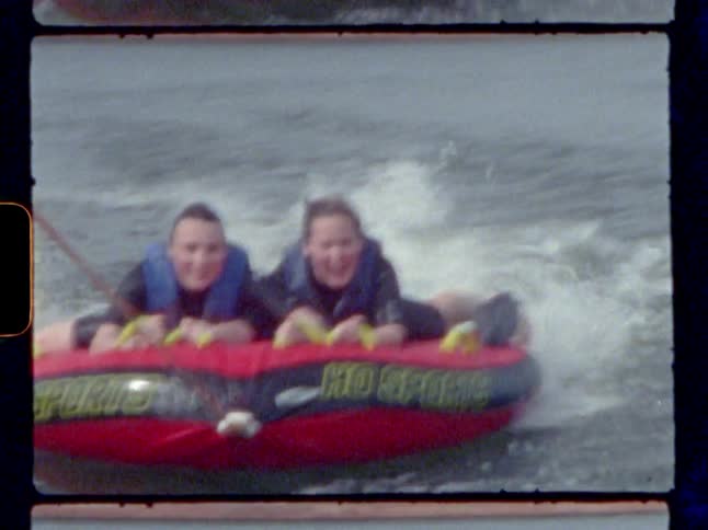 Two people on a raft being pulled by a boat with a rope
