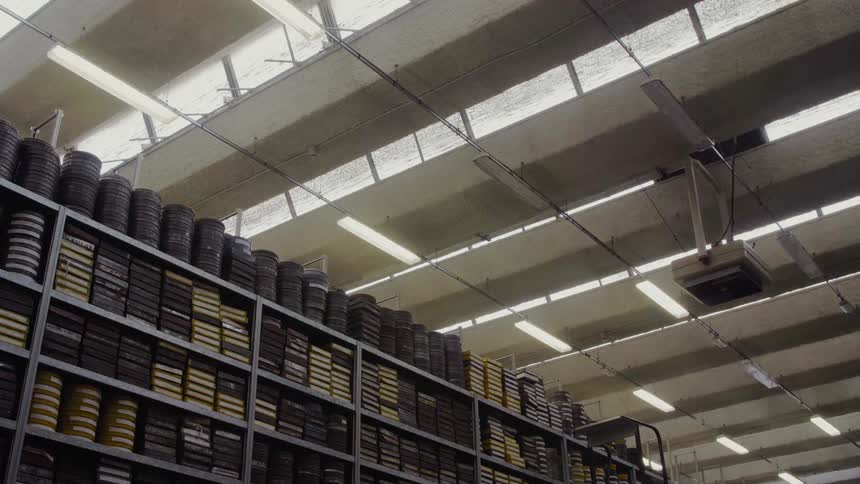 Film canisters fill a large shelving unit in a warehouse