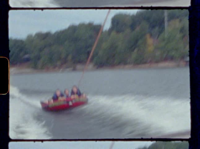 Three people on a raft being pulled by a boat with a rope