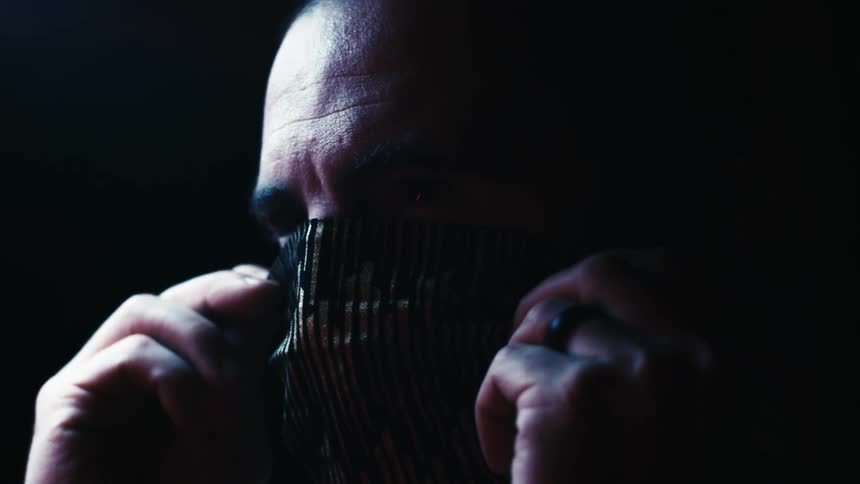 A man adjusts a patterned face mask on his face