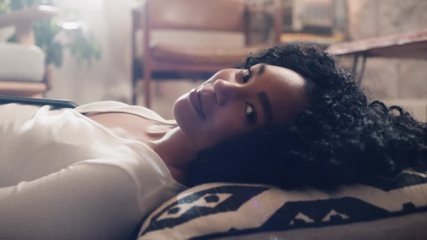 A woman lying on the living room floor with her head resting on a throw pillow