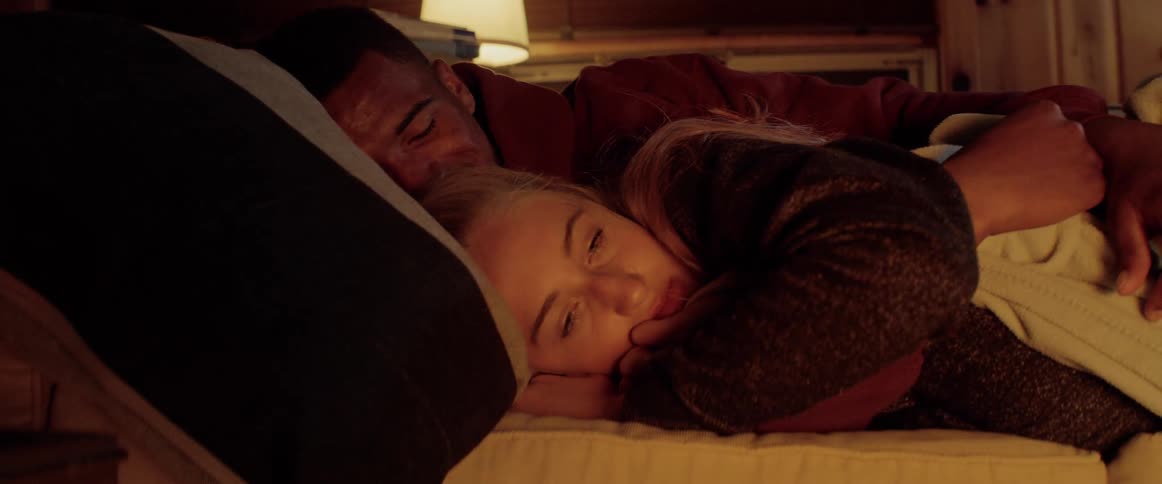 A man embracing a woman as they both rest in bed